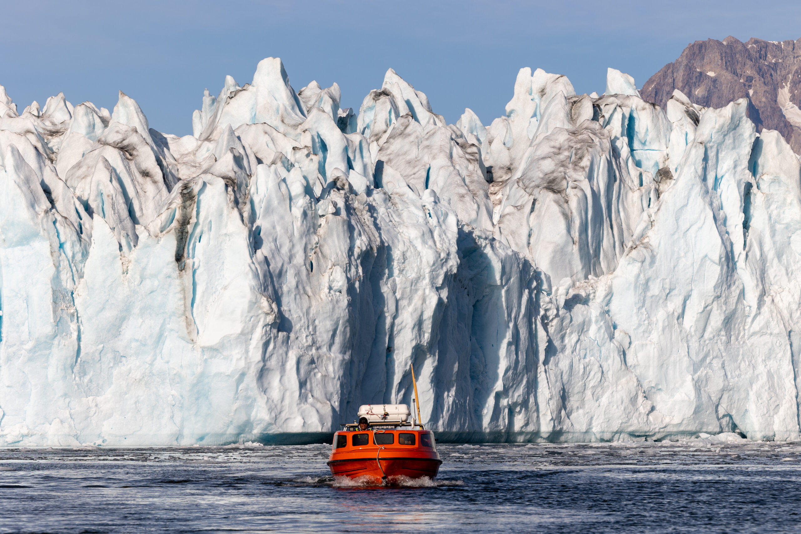 Iconic poca boat in front of Knud Rasmussen Glacier. Photo by Anna & Lucas Jahn - Visit East Greenland