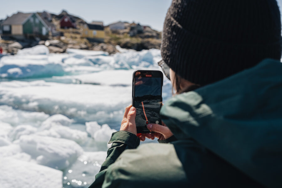 Tourist capturing settlement in East Greenland. Photo by Filip Gielda - Visit East Greenland