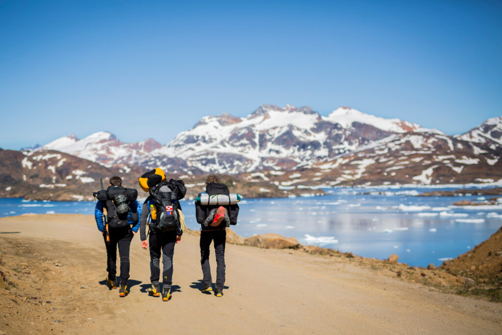 Three hikers making their way out of Tasiilaq along the fjord. Photo by Aningaaq Rosing Carlsen - Visit Greenland