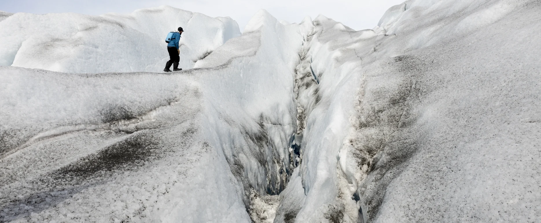 Adventurer walking along a glacial crevasse in East Greenland. Photo by Oscar Scott Carl - Visit East Greenland