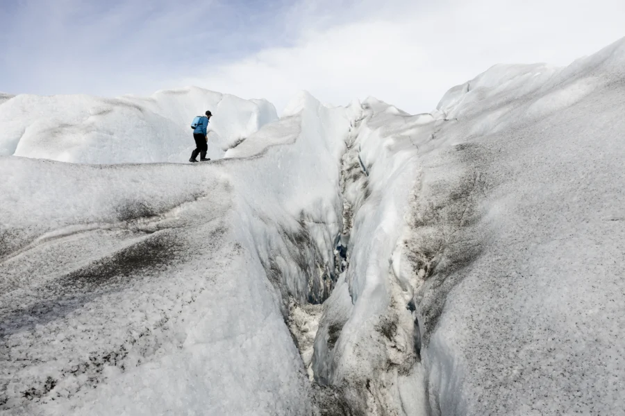 Adventurer walking along a glacial crevasse in East Greenland. Photo by Oscar Scott Carl - Visit East Greenland