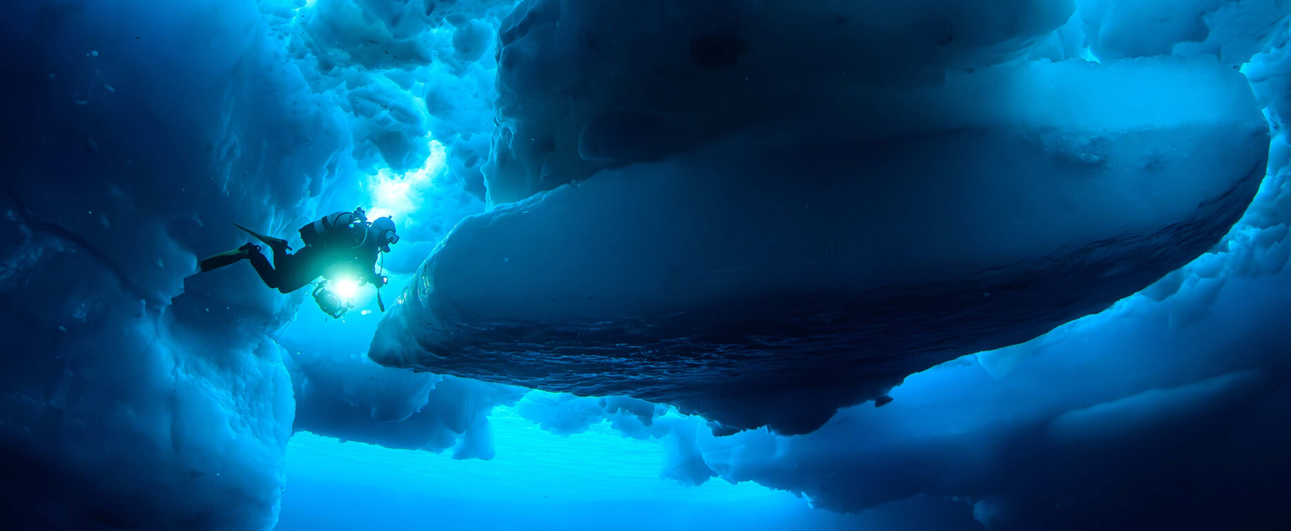 A diver approaching an iceberg from beneath in East Greenland.